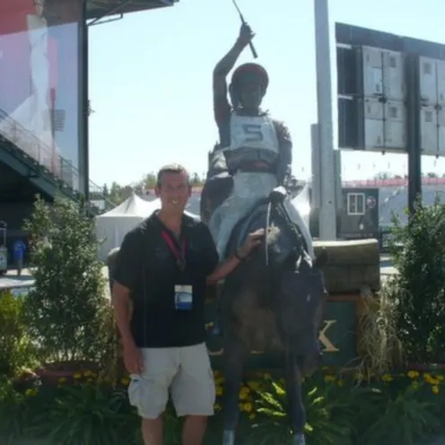 Dr. Browning with statue of a jockey at a racetrack